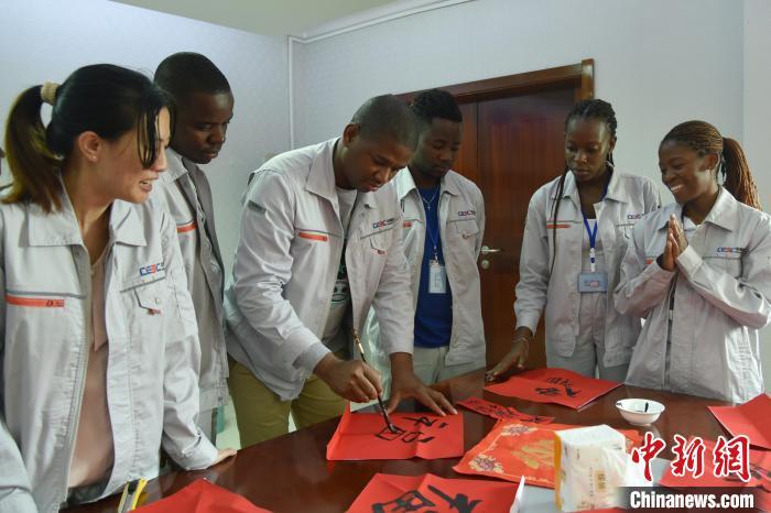 圖為春節(jié)文化活動現(xiàn)場，中外員工體驗寫福字?！≈袊芙ǜ鹬迚谓ㄔO公司供圖